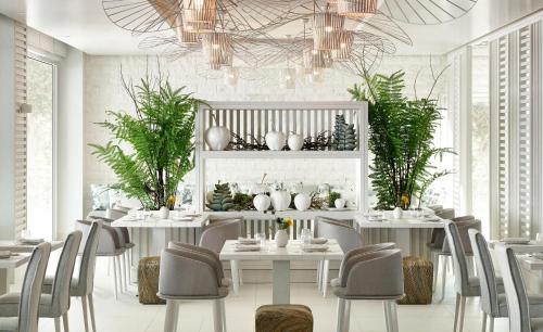 a dining room with white tables and chairs at Ikos Aria in Kefalos