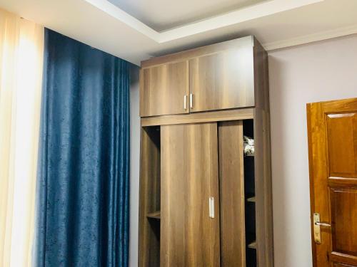 a closet with wooden cabinets and a blue curtain at ROBERT Villa APARTMENT in Kigali