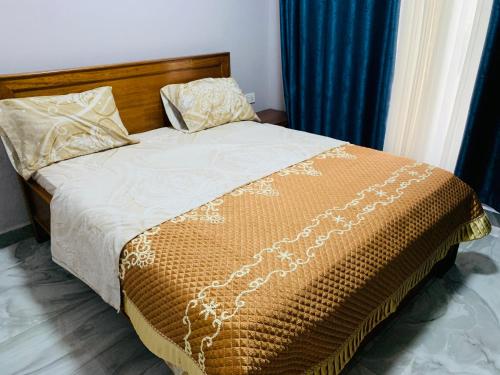 a bed with a brown and white comforter and pillows at ROBERT Villa APARTMENT in Kigali