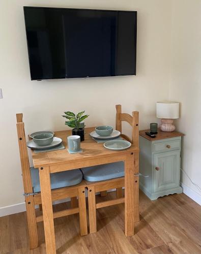 ein Holztisch mit Tellern und ein Fernseher an der Wand in der Unterkunft McCaffertys in Drumahayre