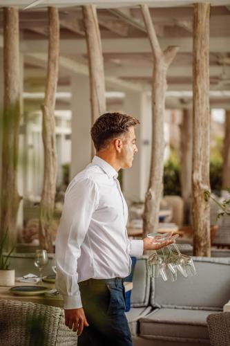 a man in a white shirt holding wine glasses at Ikos Aria in Kefalos