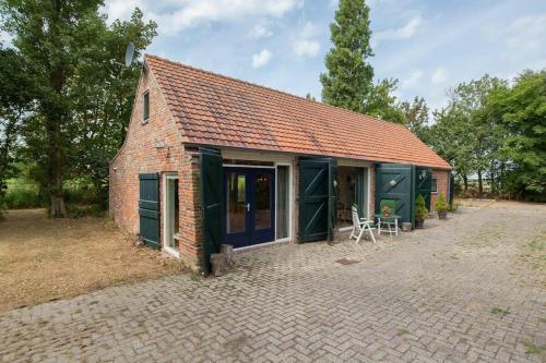 a small brick house with green doors and a patio at Hello Zeeland - Vakantiehuis Het Blauwe Hof in Koudekerke