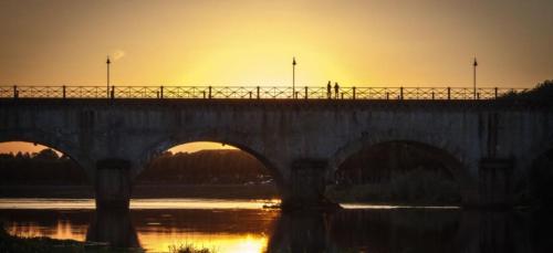 a bridge over a river with the sun setting behind it at Castle Of Saint Germain Des Rives in Saint-Germain-des-Rives