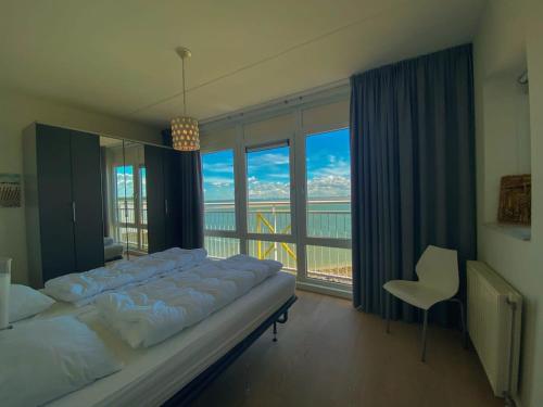 ein großes Bett in einem Zimmer mit einem großen Fenster in der Unterkunft Hello Zeeland - Appartement Port Scaldis 19-042 in Breskens