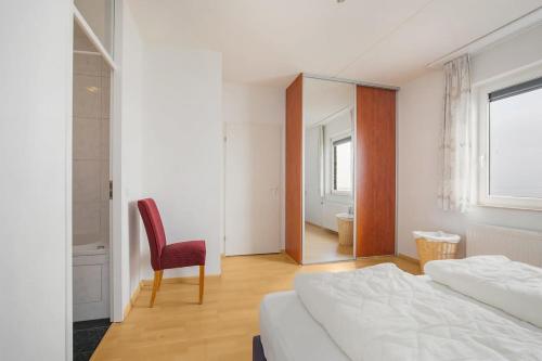 a bedroom with a bed and a chair and a mirror at Hello Zeeland - Appartement Port Scaldis 13-112 in Breskens