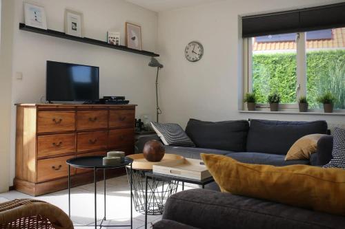 a living room with a couch and a tv at Hello Zeeland - Vakantiehuis Schelde 148 in Breskens