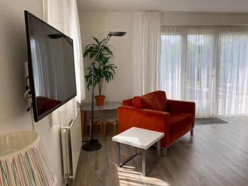 a living room with a red chair and a flat screen tv at Hello Zeeland - Vakantiehuis Zwin 182 in Breskens