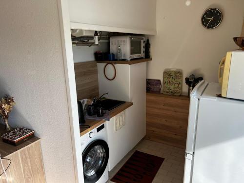 une cuisine avec un lave-linge et un micro-ondes dans l'établissement Appartement proche Bordeaux et Aéroport, à Mérignac
