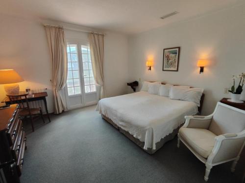 ein Schlafzimmer mit einem weißen Bett und einem Stuhl in der Unterkunft Hôtel Saint Andre in Saint-Tropez