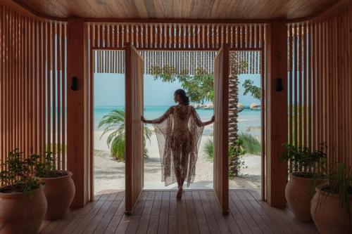 a woman walking out of a door into the beach at Nujuma, a Ritz-Carlton Reserve in Ḩanak