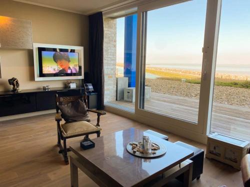 a living room with a couch and a table and a tv at Hello Zeeland - Appartement Port Scaldis 01-001 in Breskens