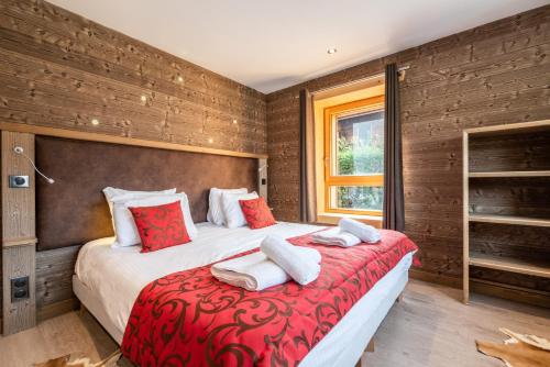 une chambre avec un grand lit avec des oreillers rouges et blancs dans l'établissement FLOCON Appartement 3 chambres, centre de Morzine, à Morzine