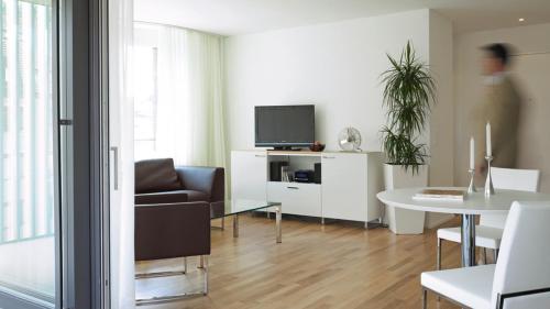 a living room with a couch and a table with a tv at City Apartments in Zug