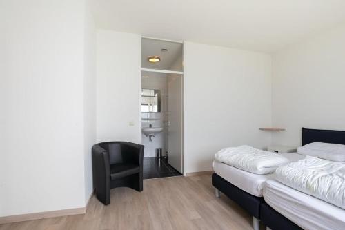a bedroom with a bed and a black chair at Hello Zeeland - Appartement Port Scaldis 11-112 in Breskens