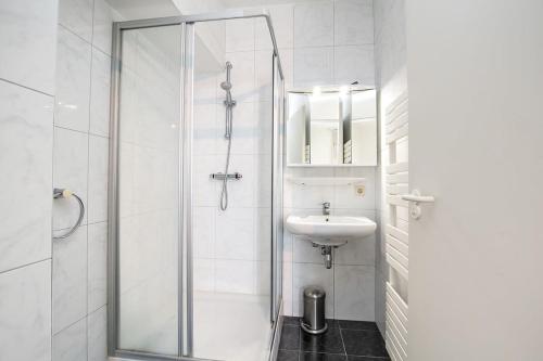 a white bathroom with a shower and a sink at Hello Zeeland - Appartement Port Scaldis 11-112 in Breskens