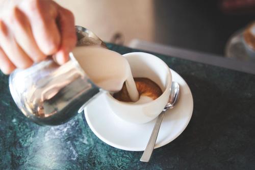 a person pouring milk into a cup of coffee at Hotel Mondolé - Azzurro Club in Prato Nevoso