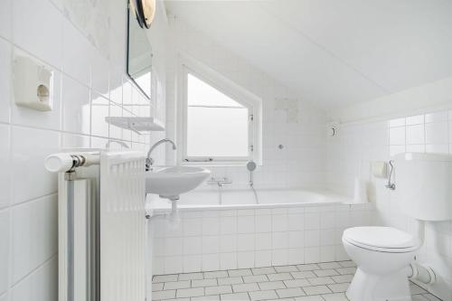 a white bathroom with a toilet and a sink at Hello Zeeland - Vakantiehuis Schelde 194 in Breskens