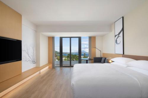 a bedroom with a white bed and a television at Fairfield by Marriott Shenzhen Dameisha in Shenzhen