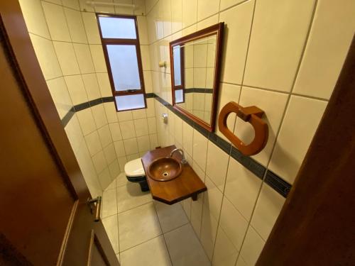 un piccolo bagno con servizi igienici e specchio di Apartamento quadra mar a Meia Praia