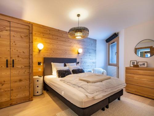 une chambre avec un grand lit avec un mur en bois dans l'établissement Appartement Neuf 4* Méribel-Mottaret - 85m², 6 pers, Balcon, Jardin, Garage - Proche Pistes et Commerces - FR-1-355-212, à Les Allues