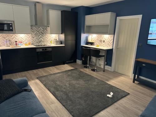 a kitchen with blue walls and white cabinets and a rug at Cozy Apartment in Stoke-on-Trent One double bed in Stoke on Trent