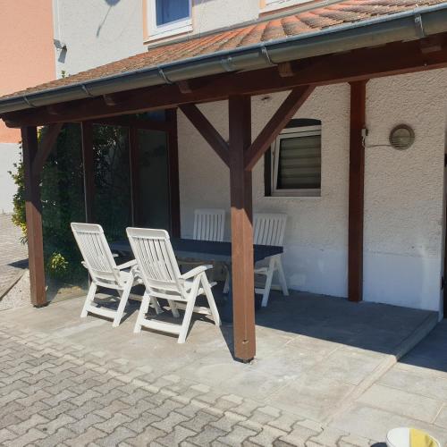 two white chairs and a table on a patio at FeWo PAN in Pfarrkirchen