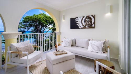 Una sala de estar con un sofá y sillas en un balcón. en Sapphire Beach 213 apts, en Christ Church