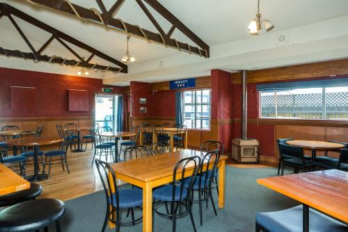 a restaurant with tables and chairs in a room at Ocean Beach Hotel in Dunedin