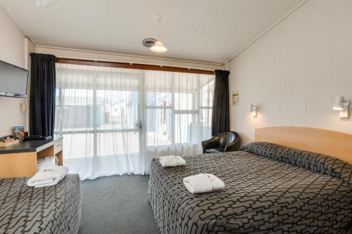 Habitación de hotel con 2 camas y ventana en Ocean Beach Hotel, en Dunedin