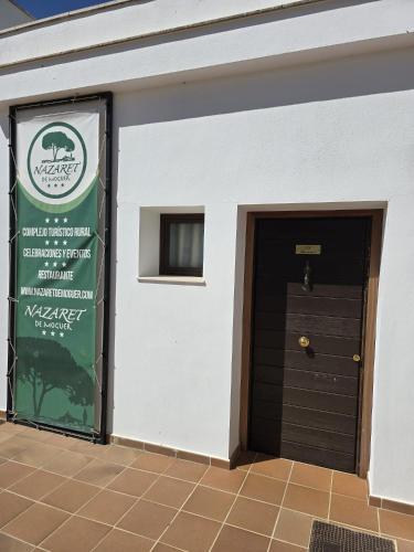 a building with a door and a sign on it at Complejo Turístico Rural Nazaret De Moguer in Moguer