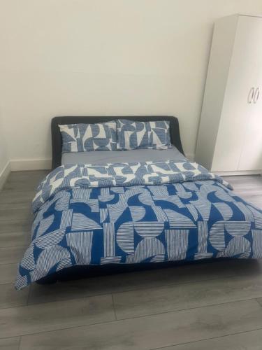 a bed with a blue and white comforter and pillows at Rivers in Bromley