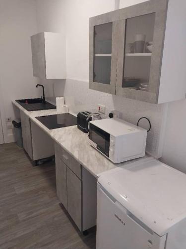 a kitchen with a counter with a microwave and a sink at Rivers in Bromley
