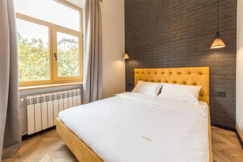 a bedroom with a large white bed with a brick wall at Idea Design Apart-Hotel Prorizna in Kyiv