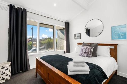 a bedroom with a bed with a mirror and a window at Belmont 3BR Townhome by Short and Long Stays in Belmont