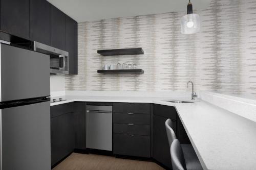 a black and white kitchen with a sink and a refrigerator at Residence Inn by Marriott Indianapolis Plainfield in Plainfield