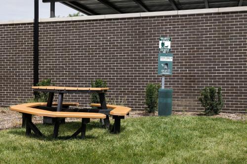 two picnic tables in the grass next to a brick wall at Residence Inn by Marriott Indianapolis Plainfield in Plainfield