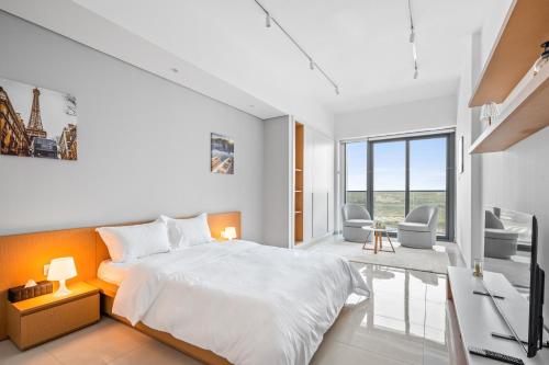a white bedroom with a bed and a desk at Spacious Studio With Dubailand Charm in Dubai