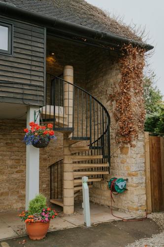 a brick house with a staircase and flowers in a pot at Redesdale Arms Hotel in Moreton in Marsh