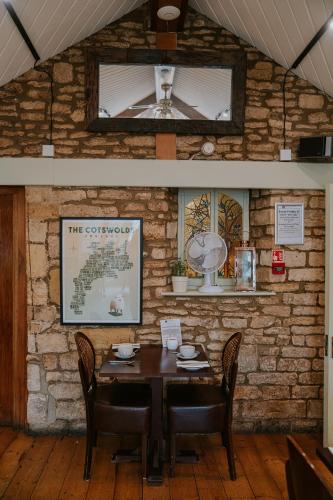 a dining room with a table and a brick wall at Redesdale Arms Hotel in Moreton in Marsh