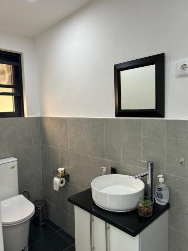 a bathroom with a sink and a toilet and a mirror at Coastal Beach Apartments in Maputo