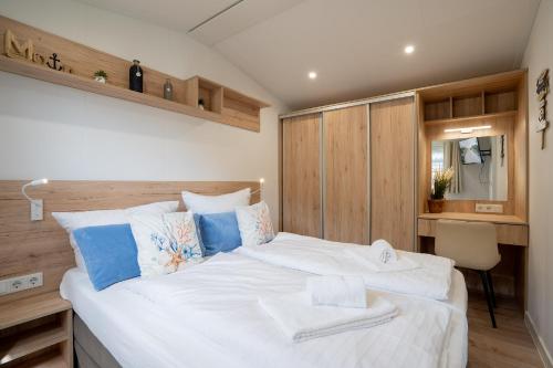 a bedroom with a large white bed with blue accents at Ostseecamp Ferienhaus "Pier 99" in Scharbeutz