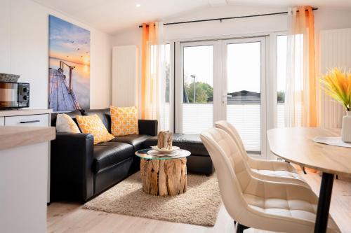 a living room with a black leather couch and a table at Ostseecamp Ferienhaus "Pier 99" in Scharbeutz