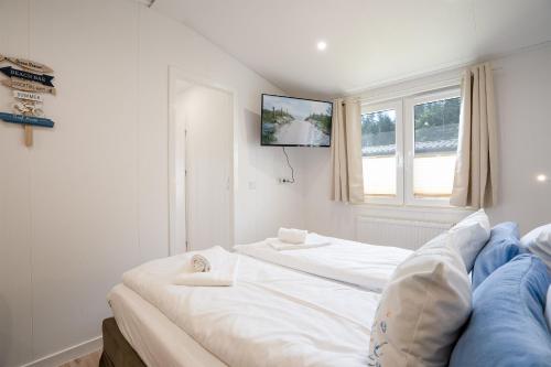 a bedroom with a white bed and a tv on the wall at Ostseecamp Ferienhaus "Pier 99" in Scharbeutz