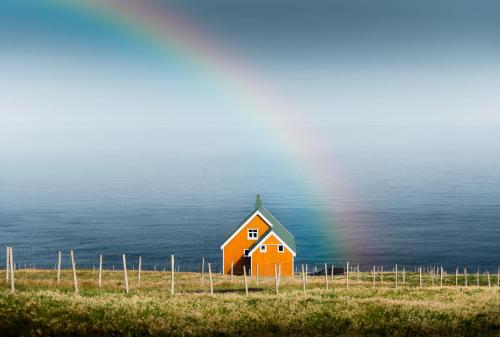 an orange house on a field with a rainbow at The Yellow House By The End Of Suuroy in Sumba