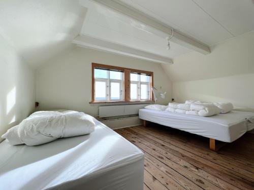 two white beds in a room with a window at The Yellow House By The End Of Suuroy in Sumba