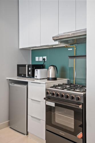 a kitchen with a stove and a microwave at Bright Studio In Vibrant Dubailand District in Dubai