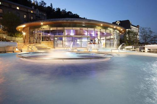 un bâtiment avec une piscine d'eau devant lui dans l'établissement Maison de plain-pied, à Le Cendre