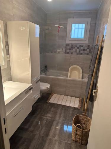 une salle de bain avec une baignoire, des toilettes et un lavabo dans l'établissement Maison de plain-pied, à Le Cendre