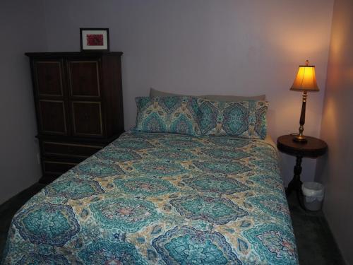 a bedroom with a bed with a quilt and a lamp at The Green Lake Getaway - Shared Lake Access! in Interlochen
