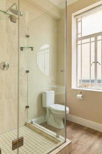 a bathroom with a toilet and a glass shower at Hotel Bruxelles in Cape Town